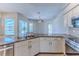 Well-lit kitchen area with granite countertops, stainless steel sink, white cabinets, and view of the backyard pool at 4044 Chesterfield Dr, Spring Hill, FL 34609