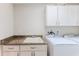Bright laundry room featuring a utility sink with granite countertops, washer, dryer, and white cabinets at 4044 Chesterfield Dr, Spring Hill, FL 34609