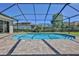 A clear shot shows a pool enclosed within a screened lanai and surrounded by brick pavers, all set under a clear blue sky at 4044 Chesterfield Dr, Spring Hill, FL 34609