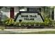 Entrance sign for Wood Trail Village, surrounded by lush greenery and landscaping at 4315 Oakland Dr, New Port Richey, FL 34653