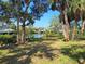 Green lawn and trees in the backyard with a canal, dock and boats in the distance at 4328 Marine Pkwy, New Port Richey, FL 34652