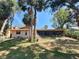 Backyard view showing the home's exterior, screened-in lanai, and mature landscaping at 4328 Marine Pkwy, New Port Richey, FL 34652