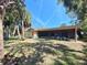 Backyard view showing the home's exterior, screened-in lanai, and landscaped lawn at 4328 Marine Pkwy, New Port Richey, FL 34652