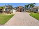 Charming home with a brick driveway, stone accents, a red door, and lush landscaping at 4423 Gevalia Dr, Brooksville, FL 34604