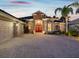 Charming home featuring stone accents, a three-car garage, and a welcoming red double-door entry at 4423 Gevalia Dr, Brooksville, FL 34604