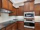 Gourmet kitchen with dark wood cabinets, stainless steel appliances, and sleek black countertops at 4423 Gevalia Dr, Brooksville, FL 34604