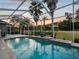 Screened pool with views of towering palm trees and a picturesque golf course at 4423 Gevalia Dr, Brooksville, FL 34604