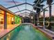 Screened pool with nice outdoor lighting and a spacious patio area surrounded by lush landscaping and palm trees at 4423 Gevalia Dr, Brooksville, FL 34604