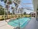 Beautiful pool and lanai surrounded by landscaping, enclosure, and a clear blue sky at 4423 Gevalia Dr, Brooksville, FL 34604