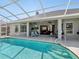 Beautiful screened-in pool and patio area with chairs, grill, and access to interior at 4423 Gevalia Dr, Brooksville, FL 34604