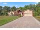 Charming single-Gathering home featuring a red-door entrance, two-car garage, brick accents, and a large brick driveway at 4469 Lake In The Woods Dr, Spring Hill, FL 34607
