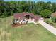 Aerial view of a beautiful home with an expansive green lawn, manicured landscaping, and a paved brick driveway at 4469 Lake In The Woods Dr, Spring Hill, FL 34607