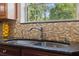 Close-up of kitchen sink with a view of the window and mosaic backsplash at 4469 Lake In The Woods Dr, Spring Hill, FL 34607