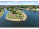 A serene aerial shot of a private island on a beautiful pond, enhanced by a cozy dock and lush greenery at 4469 Lake In The Woods Dr, Spring Hill, FL 34607