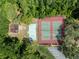 Aerial shot of red and green community tennis courts with a playground, all surrounded by a dense green forest at 4469 Lake In The Woods Dr, Spring Hill, FL 34607