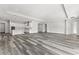 Spacious living space with gray wood-look flooring, recessed lighting and view of modern kitchen at 6063 Dusk Rose Ln, Brooksville, FL 34601