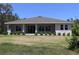The rear exterior of the house features a covered porch with large windows and manicured shrubbery at 6063 Dusk Rose Ln, Brooksville, FL 34601