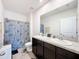 Well-lit bathroom featuring a double vanity with granite countertops, and shower with patterned curtain at 6561 Seaway Dr, Brooksville, FL 34604
