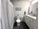 Bright bathroom featuring a toilet, shower with curtain and a vanity with a marble countertop and white cabinets at 6622 Seaview Blvd, Hudson, FL 34667