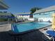 Outdoor swimming pool with lounge area, surrounded by white fencing, and colorful buildings at 6636 Timbercove Ln # 6636, New Port Richey, FL 34653