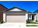 Two-car garage with concrete driveway, manicured bushes, and a small front porch at 680 Argyll Dr, Spring Hill, FL 34609