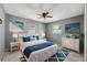 Beautiful bedroom with blue accents, coastal artwork, ceiling fan, and plank flooring at 6816 Sanderling Ln, Hudson, FL 34667