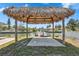 Covered tiki hut features a serene canal view and dock, perfect for relaxing outdoors at 6816 Sanderling Ln, Hudson, FL 34667