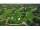Aerial view of the lush, green golf course surrounded by mature trees and a serene pond at 7529 Greystone Dr # A, Hudson, FL 34667