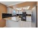 Open-concept kitchen features white cabinets, stainless steel refrigerator and black appliances at 9001 Lido Ln, Port Richey, FL 34668