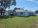 Home backyard featuring lush green lawn, privacy fence, and covered porch with a blue exterior at 9089 Dupont Ave, Spring Hill, FL 34608