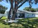 A tranquil backyard features lush green grass, a patio, and shade from mature trees offering serene outdoor living at 9089 Dupont Ave, Spring Hill, FL 34608