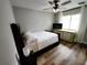 Bedroom showcasing a ceiling fan, a light green dresser and a large window with white curtains at 9089 Dupont Ave, Spring Hill, FL 34608