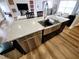 Kitchen island featuring stainless steel sink, dishwasher, quartz countertop, and wood-look floors at 9089 Dupont Ave, Spring Hill, FL 34608