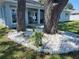 The home features unique landscaping around the trees, accented with decorative white stone and garden edging at 9089 Dupont Ave, Spring Hill, FL 34608