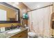 Well-lit bathroom featuring a granite countertop vanity, decorative mirror, and patterned shower curtain at 9100 Whitman Ln, Port Richey, FL 34668