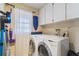 Laundry room features a washer, dryer, storage cabinets, and a bright window at 9100 Whitman Ln, Port Richey, FL 34668