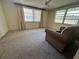 Bright living room featuring large windows, carpet, and a comfortable armchair at 9104 Lido Ln, Port Richey, FL 34668