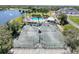 Aerial view featuring the tennis courts and community pool with surrounding landscaping and a lake at 9237 Penelope Dr, Weeki Wachee, FL 34613