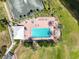Aerial view highlighting the community pool area with tennis courts, lush landscaping, and surrounding lake at 9237 Penelope Dr, Weeki Wachee, FL 34613