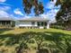 Backyard featuring lush lawn, the home's exterior, showcasing landscaping and mature trees at 9237 Penelope Dr, Weeki Wachee, FL 34613