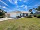 Attractive single-story home with a well-manicured lawn, mature trees, and a two-car garage on a sunny day at 9237 Penelope Dr, Weeki Wachee, FL 34613
