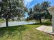 Backyard view of a scenic waterfront pond and green lawn, shaded by trees at 9336 Santa Monica Way, New Port Richey, FL 34655
