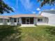 Spacious backyard with a screened lanai on a home with a white exterior, green lawn at 9336 Santa Monica Way, New Port Richey, FL 34655