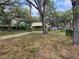 Exterior view of a green home with carport surrounded by mature trees and landscaping at 9441 Teak St, New Port Richey, FL 34654
