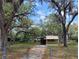 Exterior view of a one-story home with beautiful mature trees, a carport, and a chain link fence at 9441 Teak St, New Port Richey, FL 34654
