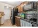 Kitchen featuring dark wood cabinets, tile backsplash, and black appliances against wood-look flooring at 9640 Northcliffe Blvd, Spring Hill, FL 34608