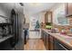 Kitchen with wood cabinets, tile backsplash, and modern appliances that flows to the living room at 9640 Northcliffe Blvd, Spring Hill, FL 34608