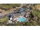 An aerial view of community center with a pool, tennis courts, parking, and golf area at 9652 Oakwood Hills Ct, New Port Richey, FL 34655