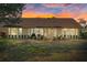 The home's back exterior at sunset with a patio, seating, grill, and a lush green lawn at 9652 Oakwood Hills Ct, New Port Richey, FL 34655