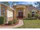 Close up of front entrance with stone pillars, red door, and manicured shrubs at 9652 Oakwood Hills Ct, New Port Richey, FL 34655
